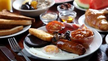 Un plato de desayuno con huevos, salchichas, tomates y tostadas.