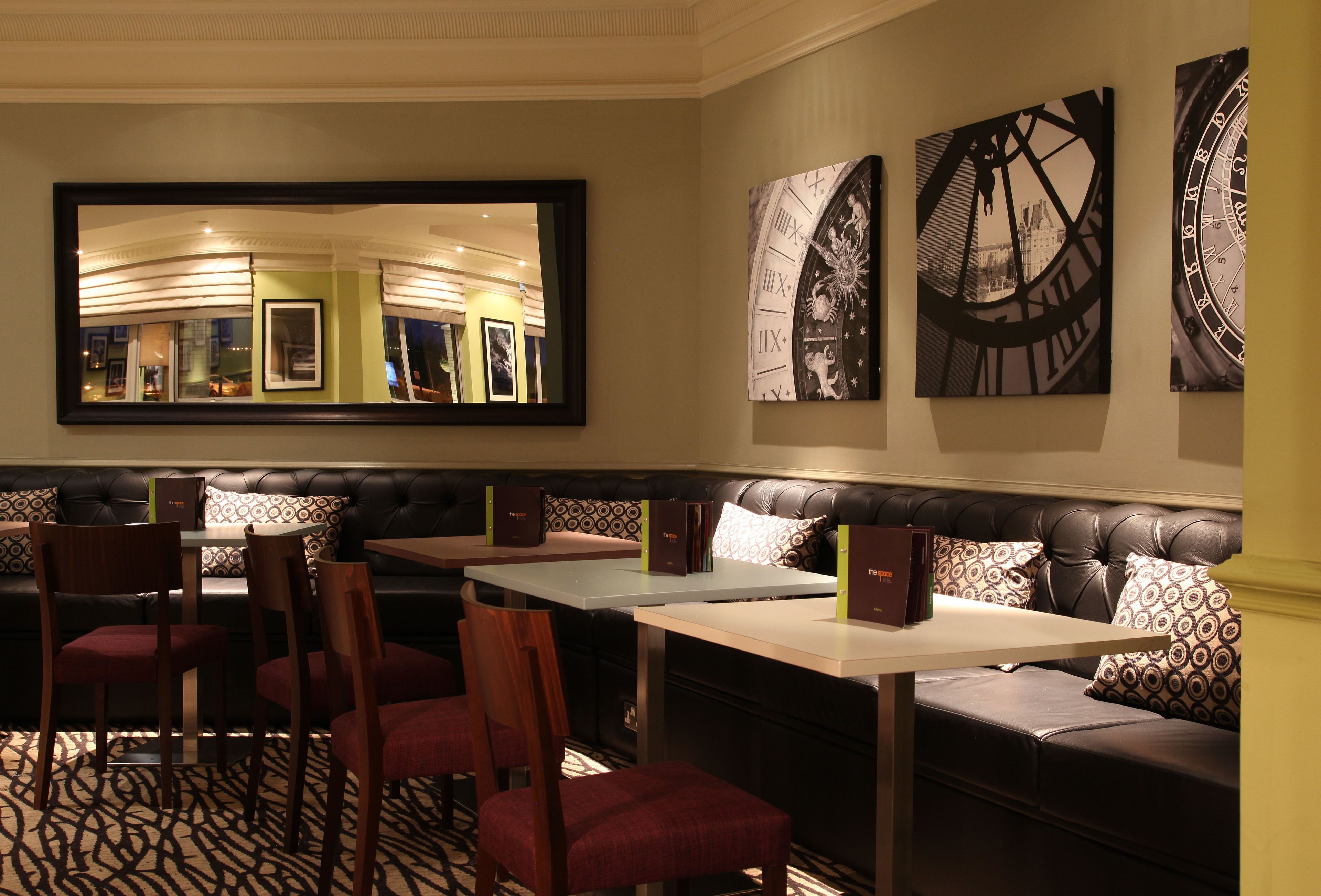 A restaurant with a mirrored wall, leather seating, and a patterned floor.