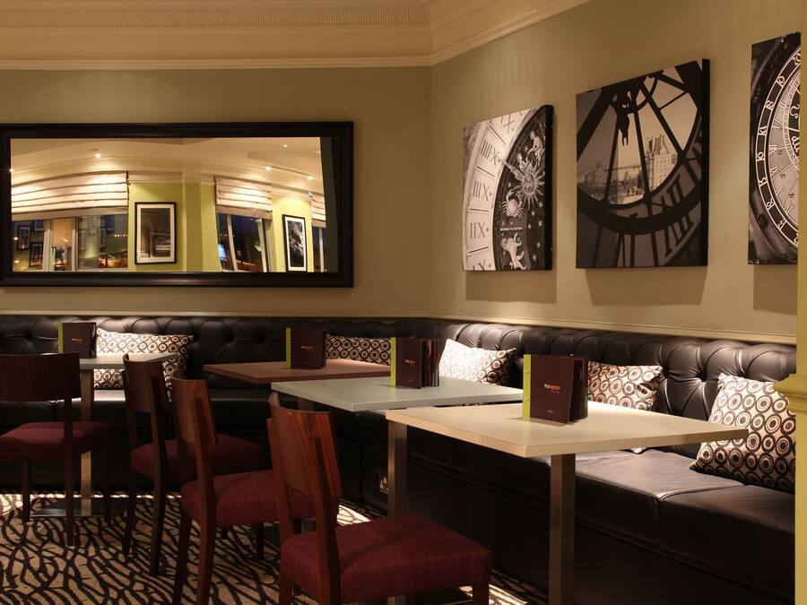 A restaurant with a mirrored wall, leather seating, and a patterned floor.