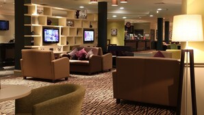 A hotel lobby with sofas, a television, and a bar area. - DoubleTree by Hilton Glasgow Strathclyde (Bellshill)