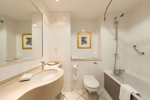 A modern bathroom with a freestanding bathtub, a separate shower area, a toilet, and a sink with a mirror. - DoubleTree by Hilton Glasgow Strathclyde (Bellshill)