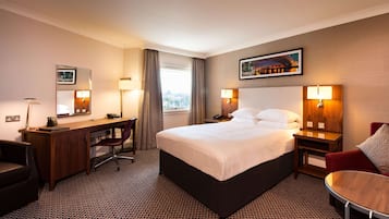 Une chambre d’hôtel avec un lit, un bureau, une chaise et une petite table.