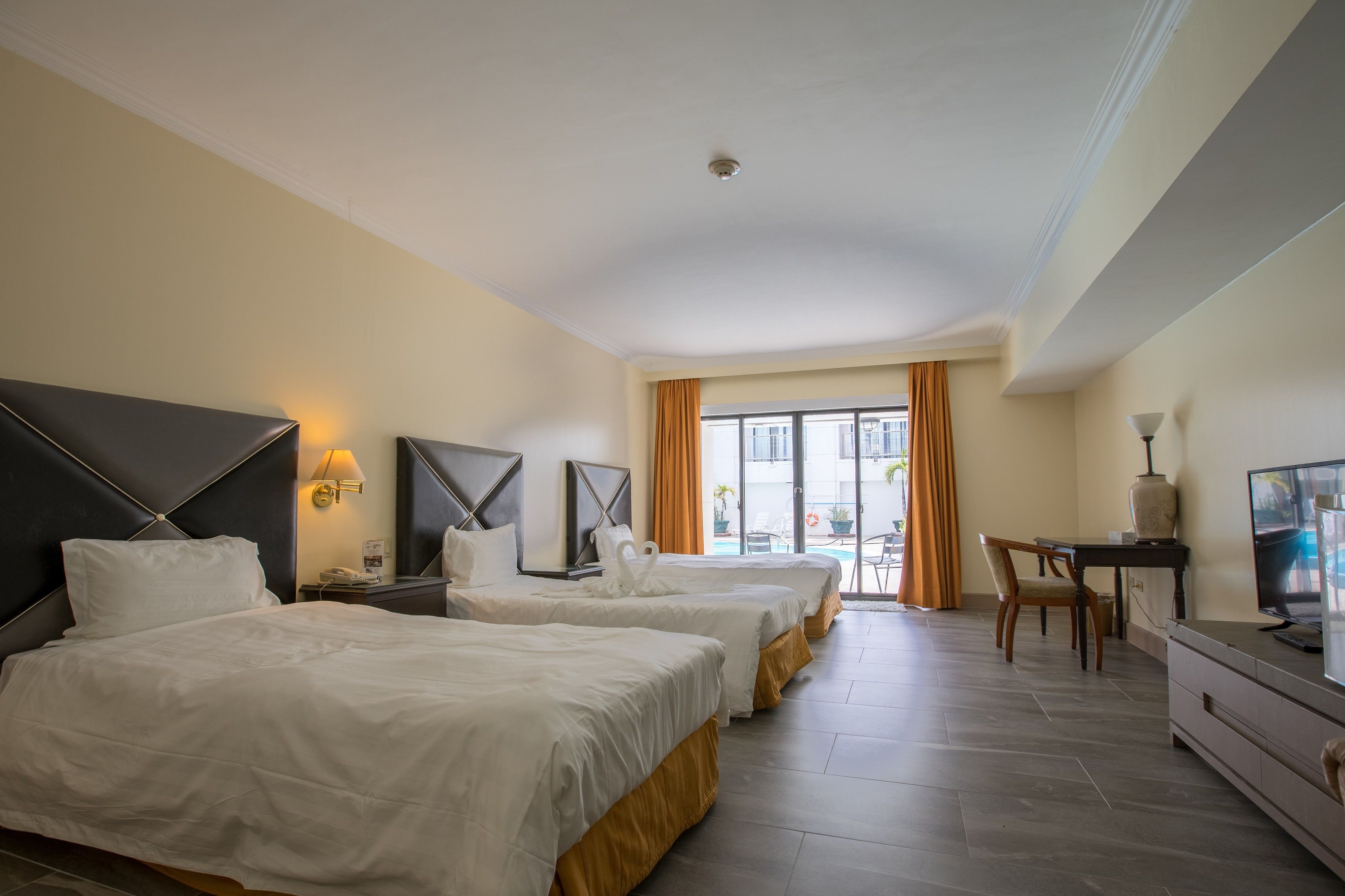 Une chambre d’hôtel avec deux lits, un bureau, une télévision et une vue sur l’extérieur.