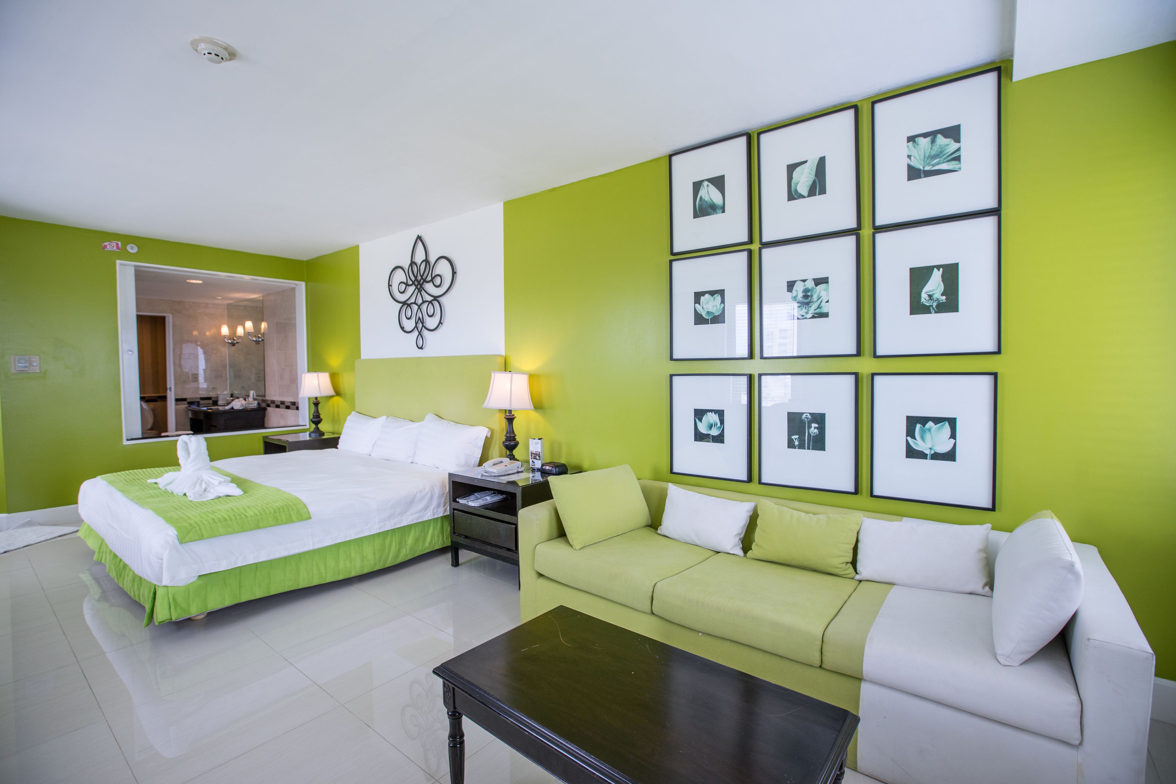 A hotel room with a bed, a green sofa, a coffee table, and framed pictures on the wall.