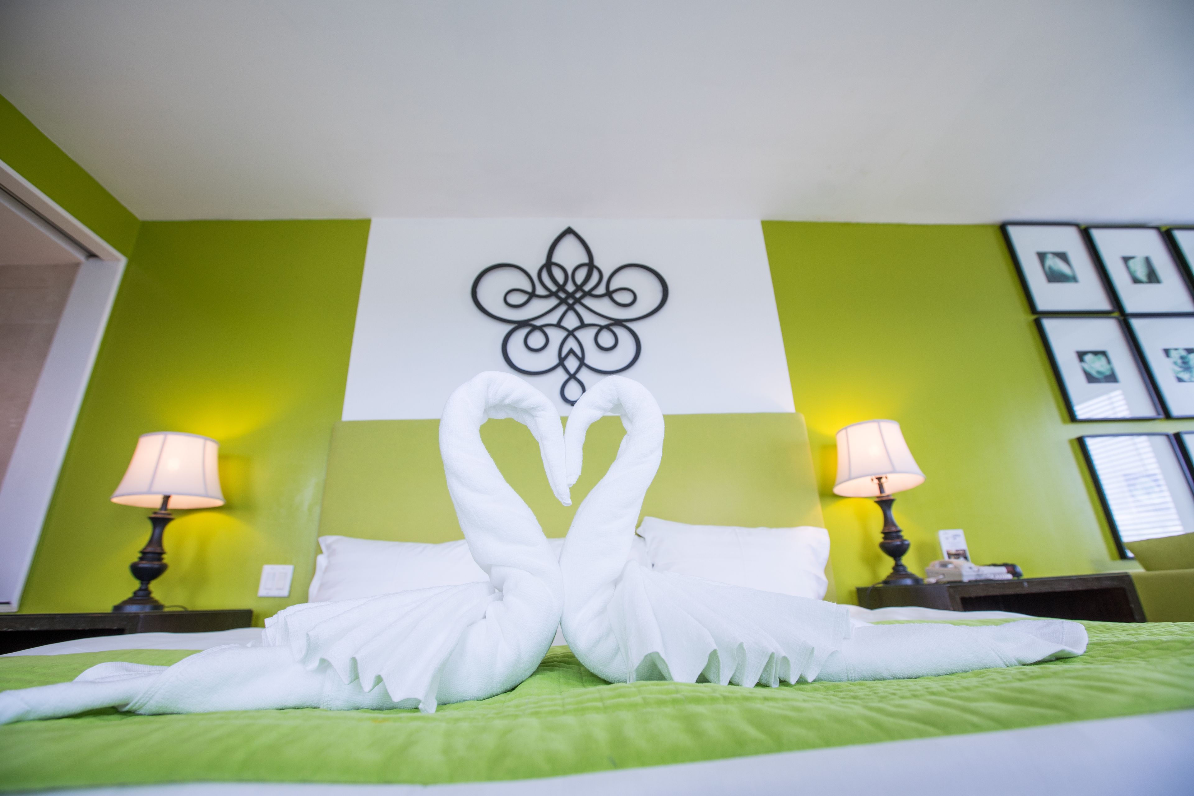 A hotel room with a bed, green walls, and a decorative wall piece.