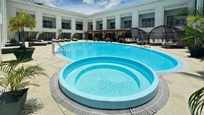Zona de piscina con piscina circular, sillas de descanso y sombrillas.