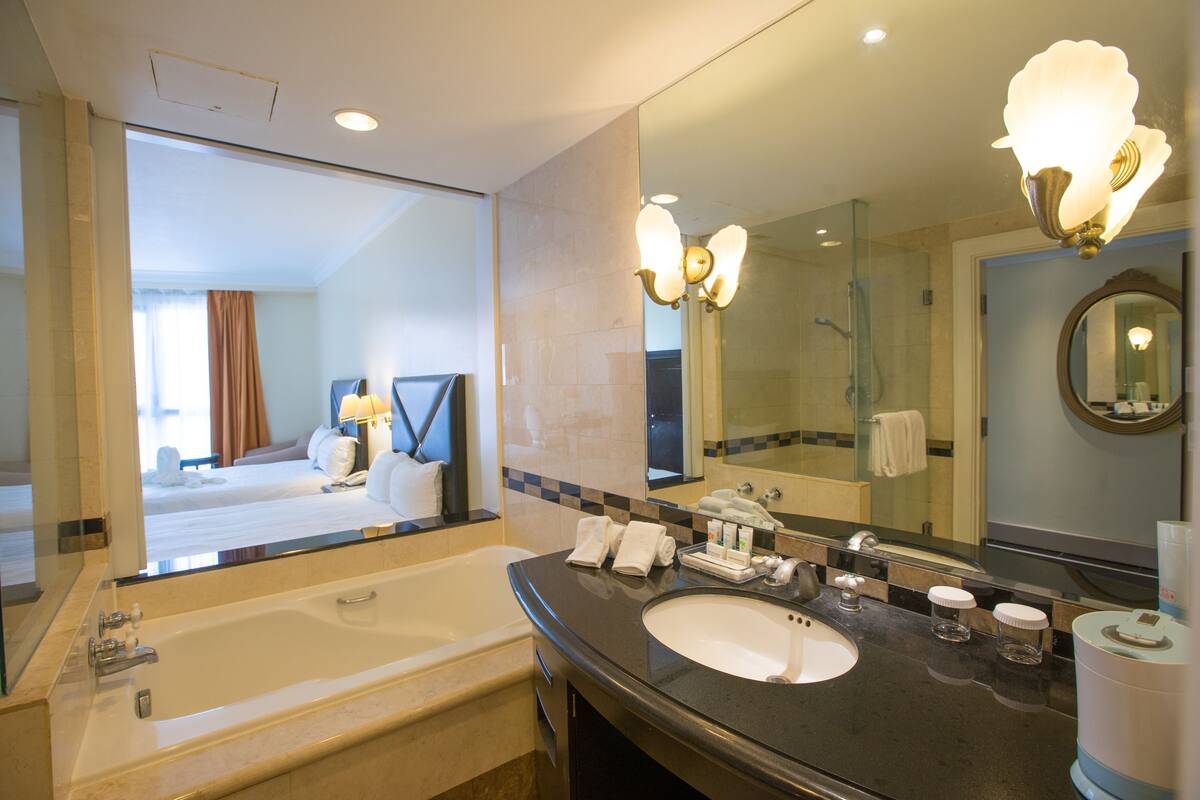 A hotel bathroom with a large bathtub, a sink, and a mirror.