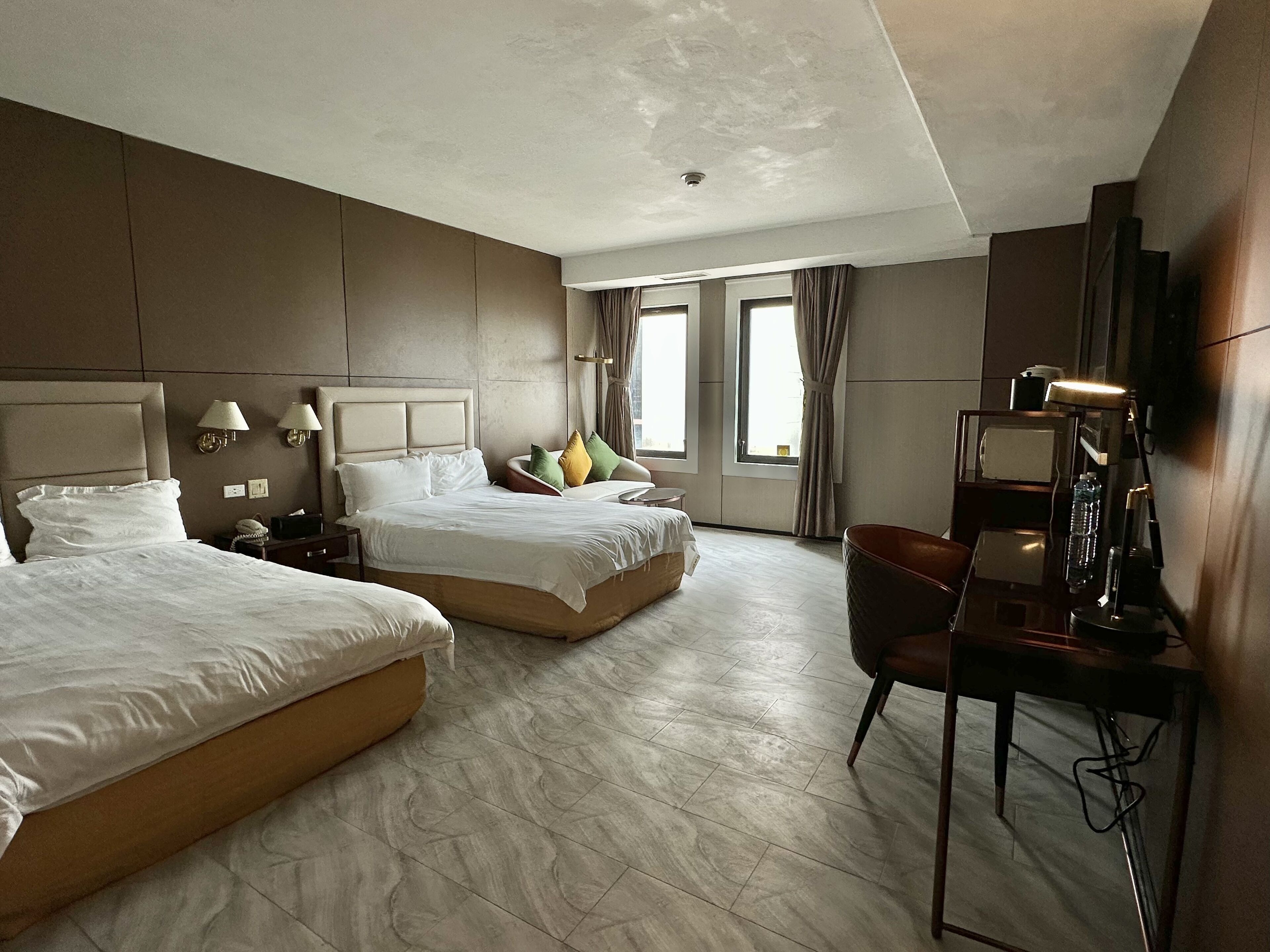 Une chambre d’hôtel avec deux lits, un bureau, une chaise et un téléviseur.