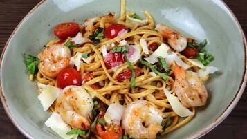 A bowl of spaghetti with shrimp, cherry tomatoes, and herbs.
