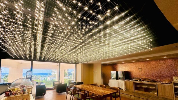 Un comedor moderno con un alto techo decorado con luces colgantes, una mesa de madera y sillas.