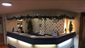 Un comptoir d’accueil décoré d’une guirlande de Noël, d’un petit sapin de Noël et d’un certificat encadré.