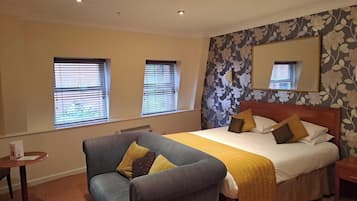 Una habitación de hotel con cama, sofá, una mesita y un espejo en la pared.