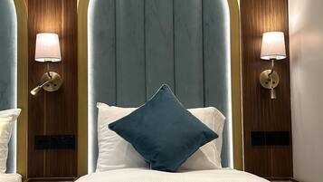 A hotel room with a large bed, two bedside tables, a nightstand, and a wall-mounted lamp.