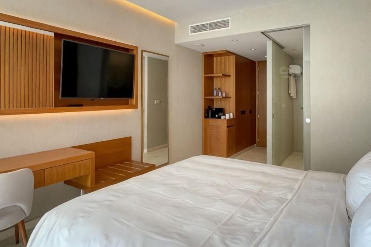 A hotel room with a bed, a desk, a television, and a wardrobe.