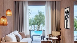 Habitación de hotel moderna con un ventanal grande, un sofá, una silla, una mesita y vista a la piscina.