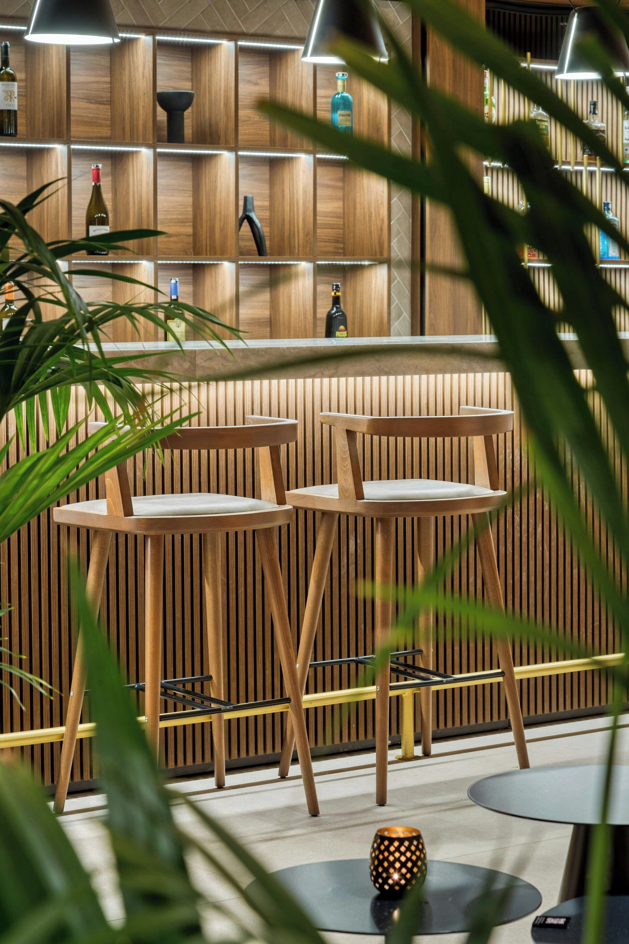 Zona de bar moderna con paredes de listones de madera, diversas opciones de asientos y una variedad de botellas en estanterías.