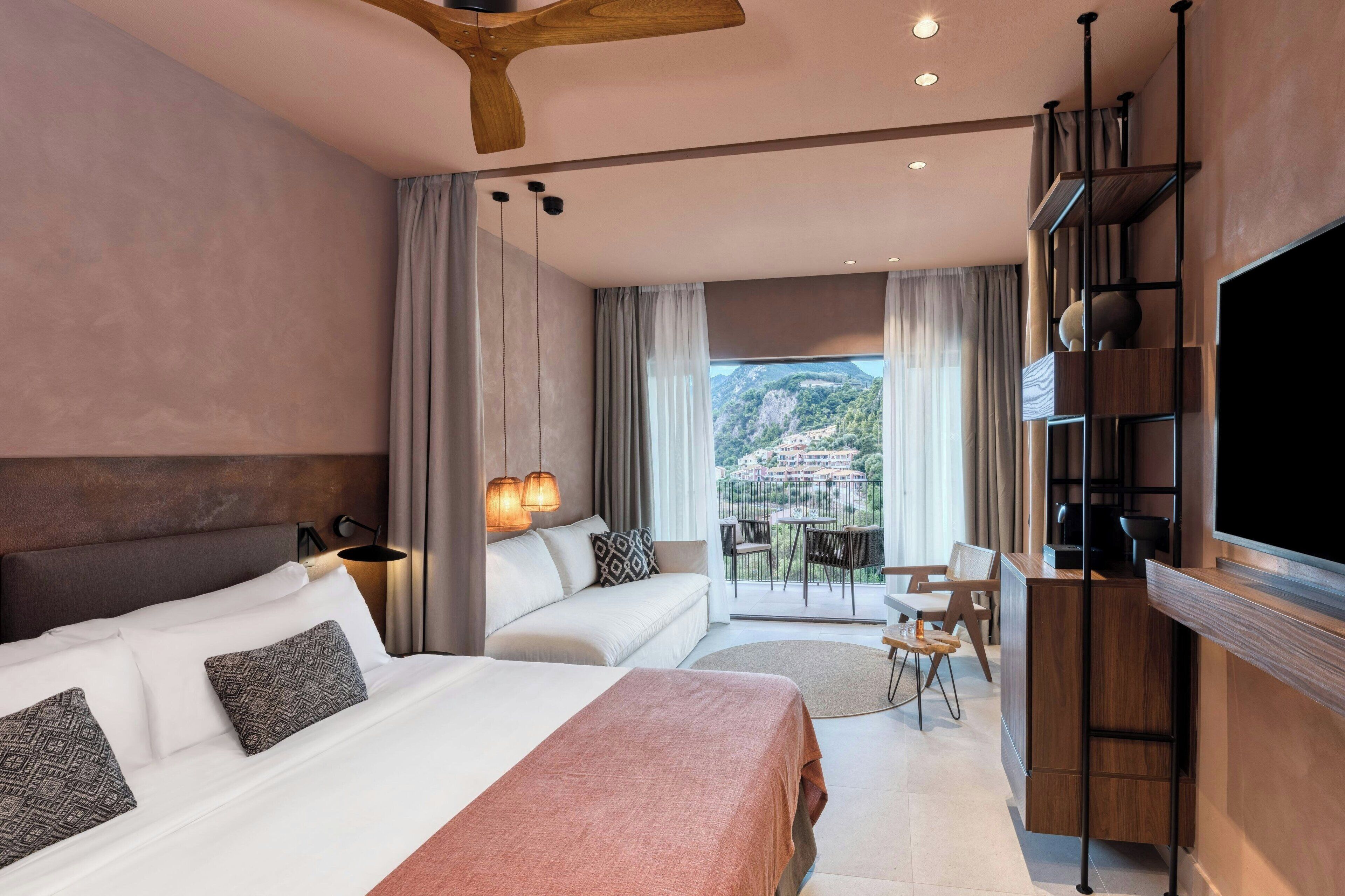 Una habitación de hotel moderna con una cama grande, un sofá, un balcón con vistas a la ciudad y un televisor.