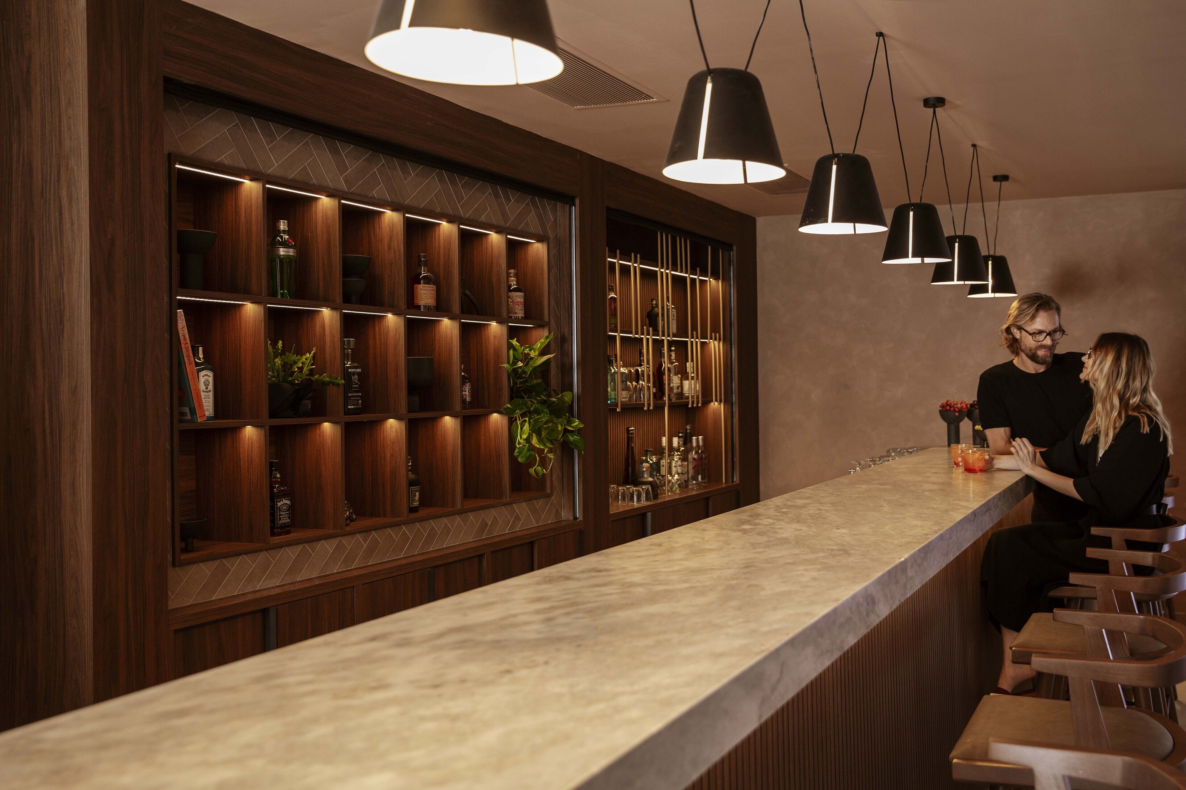 A bar area with wooden shelves and hanging pendant lights.