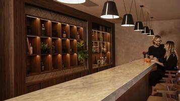 Una zona de bar con estanterías de madera y lámparas colgantes.