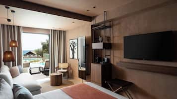 Una habitación de hotel moderna con una cama grande, un televisor montado en la pared, una zona de estar con vistas a la piscina y un balcón con cortinas.