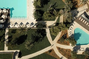 An aerial view of a resort with a swimming pool, lounge areas, and landscaped gardens. - Domes of Corfu Autograph Collection (Corfu)