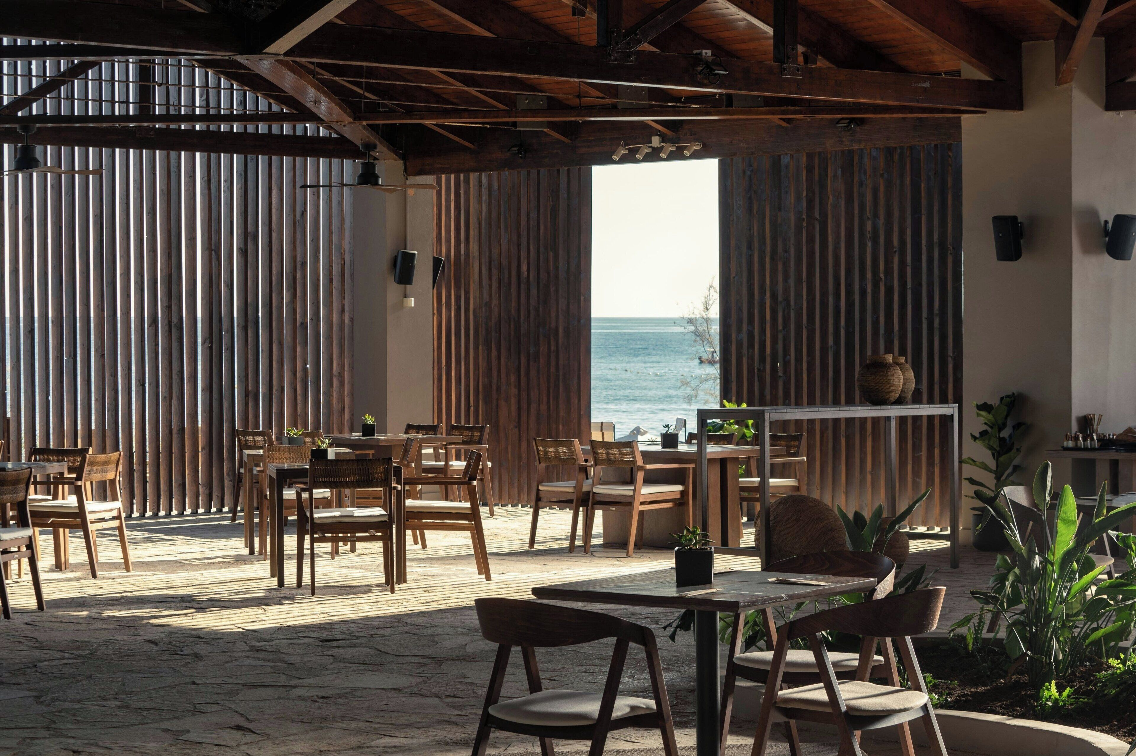 An outdoor dining area with wooden furniture and a view of the sea.