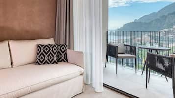 A balcony with a sofa and chairs, overlooking a coastal view.