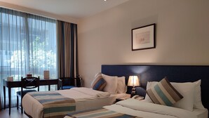 A hotel room with two beds, a desk, a chair, a lamp, and a framed picture on the wall. - Casa D Or Hotel (Beirut)