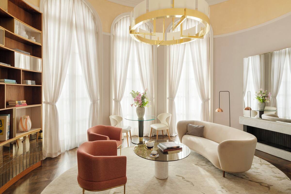 A modern living room with a sofa, armchairs, a coffee table, and a bookshelf.