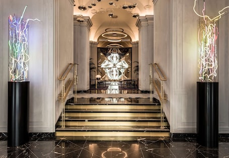 A grand staircase with a chandelier and modern light installations at the top.