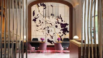 A reception area with a marble wall, a wooden reception desk, and pink chairs.