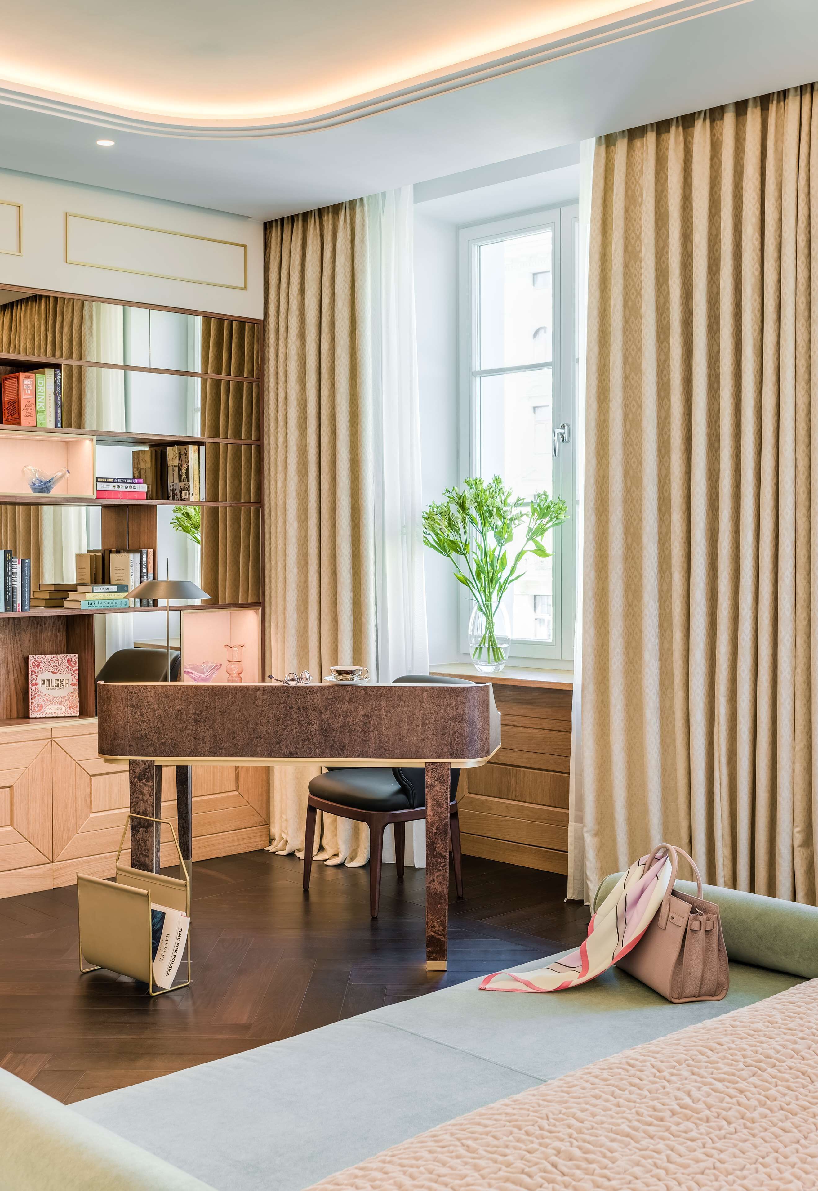 A modern room with a desk, bookshelves, a window with curtains, and a plant.