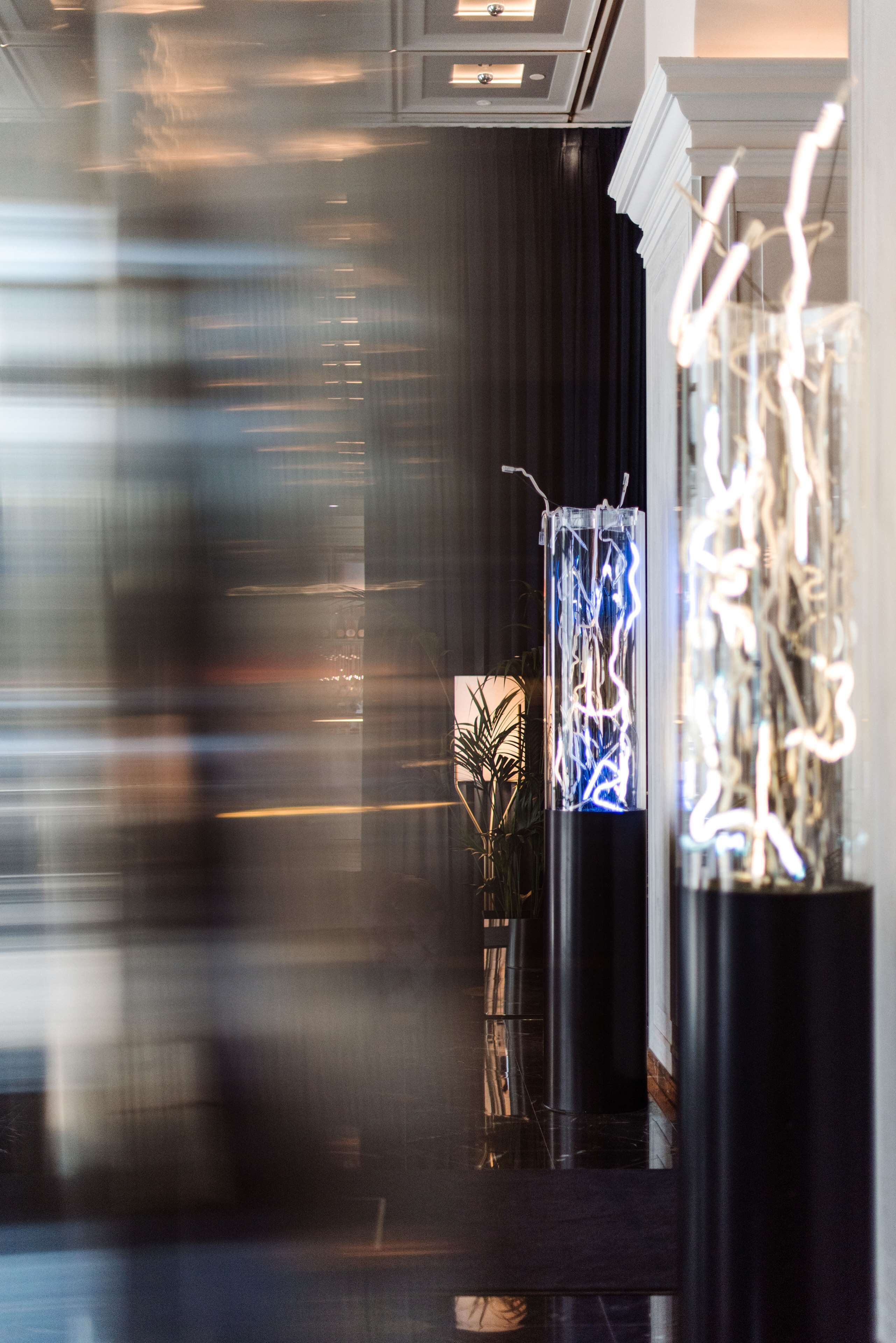 A modern interior with a dark curtain backdrop, a glass sculpture, and a potted plant.