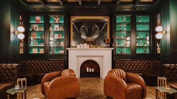 A luxurious lounge with leather sofas, a fireplace, and a wall adorned with framed pictures and a globe.