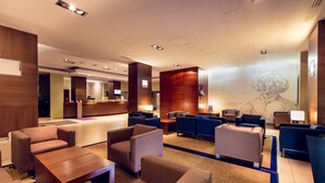 A modern hotel lobby with a reception desk, seating area, and a large mural on the wall. - Hotel Mercure Torun Centrum (Torun)