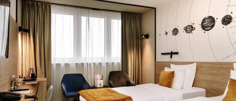 A hotel room with a bed, a desk, a chair, and a small table with a coffee maker.