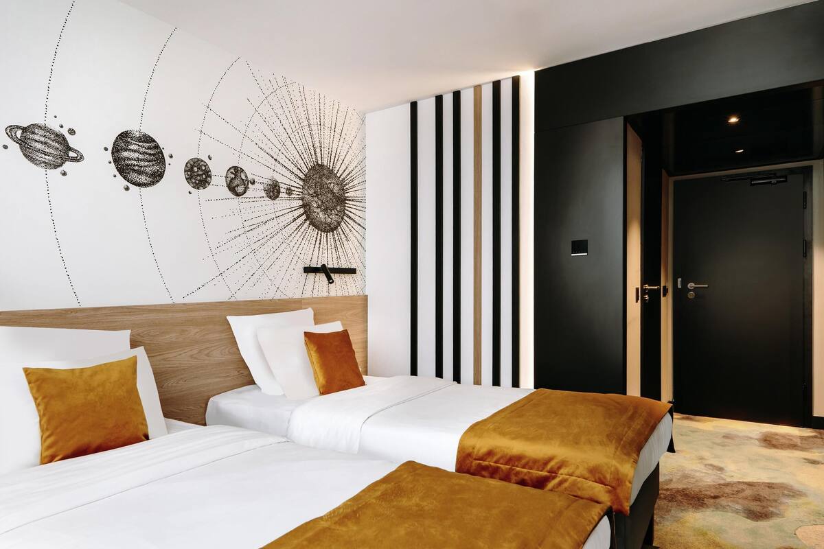 A hotel room with a large bed, a wall art piece, a door, and a striped panel.