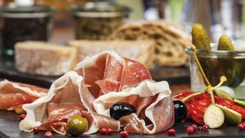 Una tabla de embutidos con diferentes carnes, aceitunas y pepinillos.