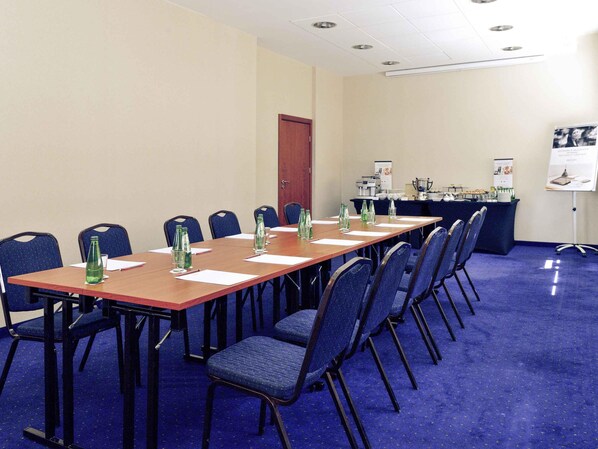 Un salón de conferencias con una larga mesa, sillas y una mesa de buffet.