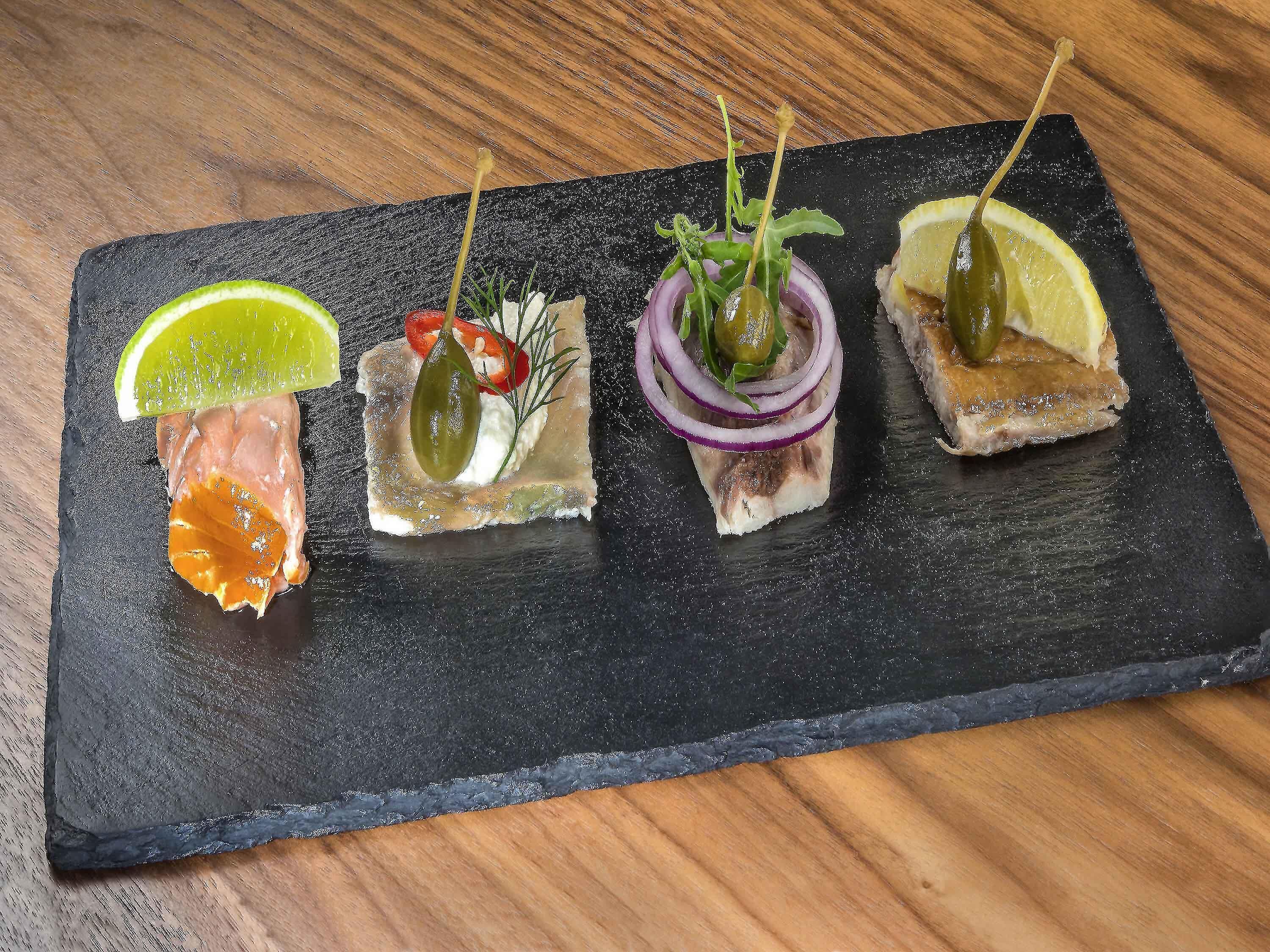 Una tabla de pizarra con cuatro diferentes aperitivos.