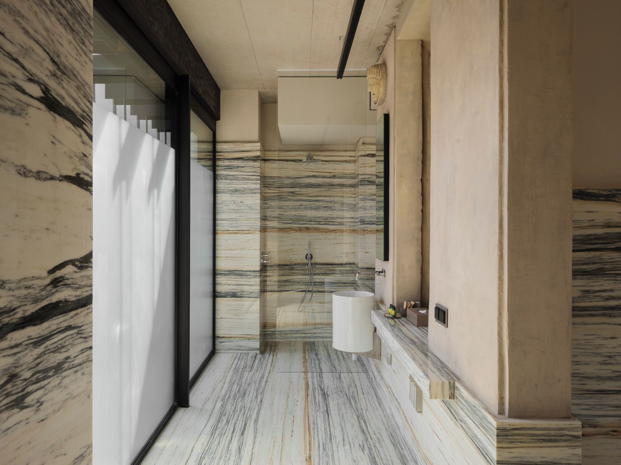 A modern bathroom with a marble floor, a large sink, and a glass shower enclosure.