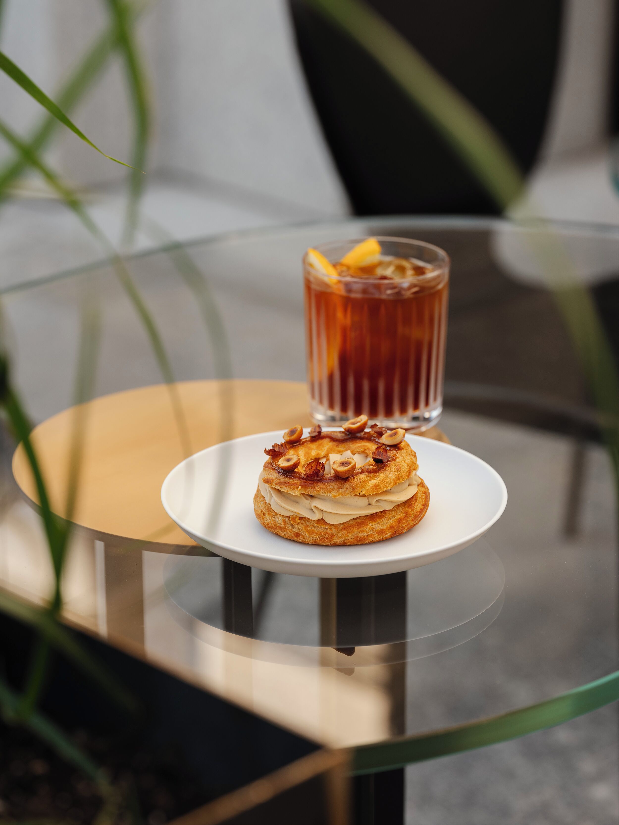 A dessert on a glass table with a beverage in the background.