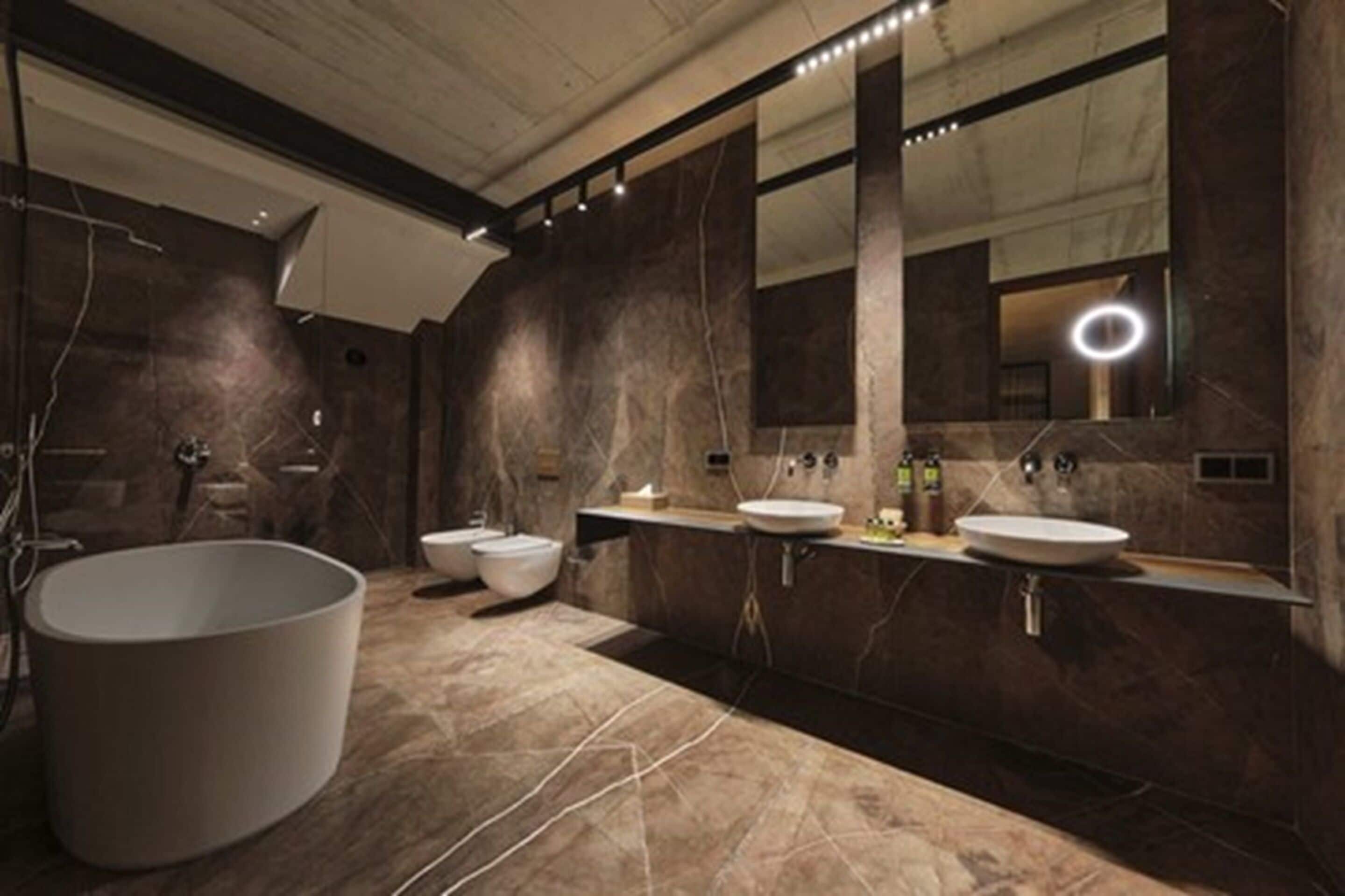 A modern bathroom with a large bathtub, two sinks, and a large mirror.