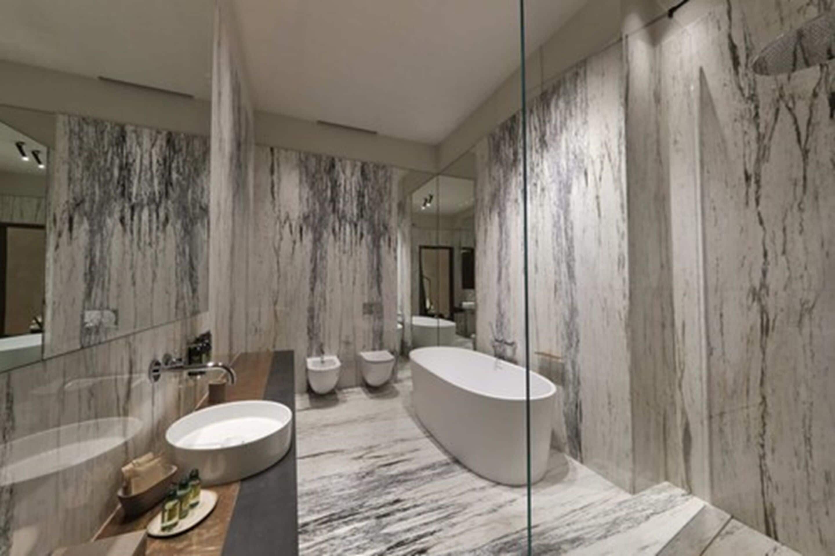 A modern bathroom with a freestanding bathtub, a large vanity with a sink, and two toilets.