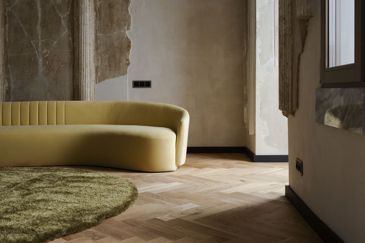 Una habitación con sofá amarillo, alfombra verde y suelo de madera.