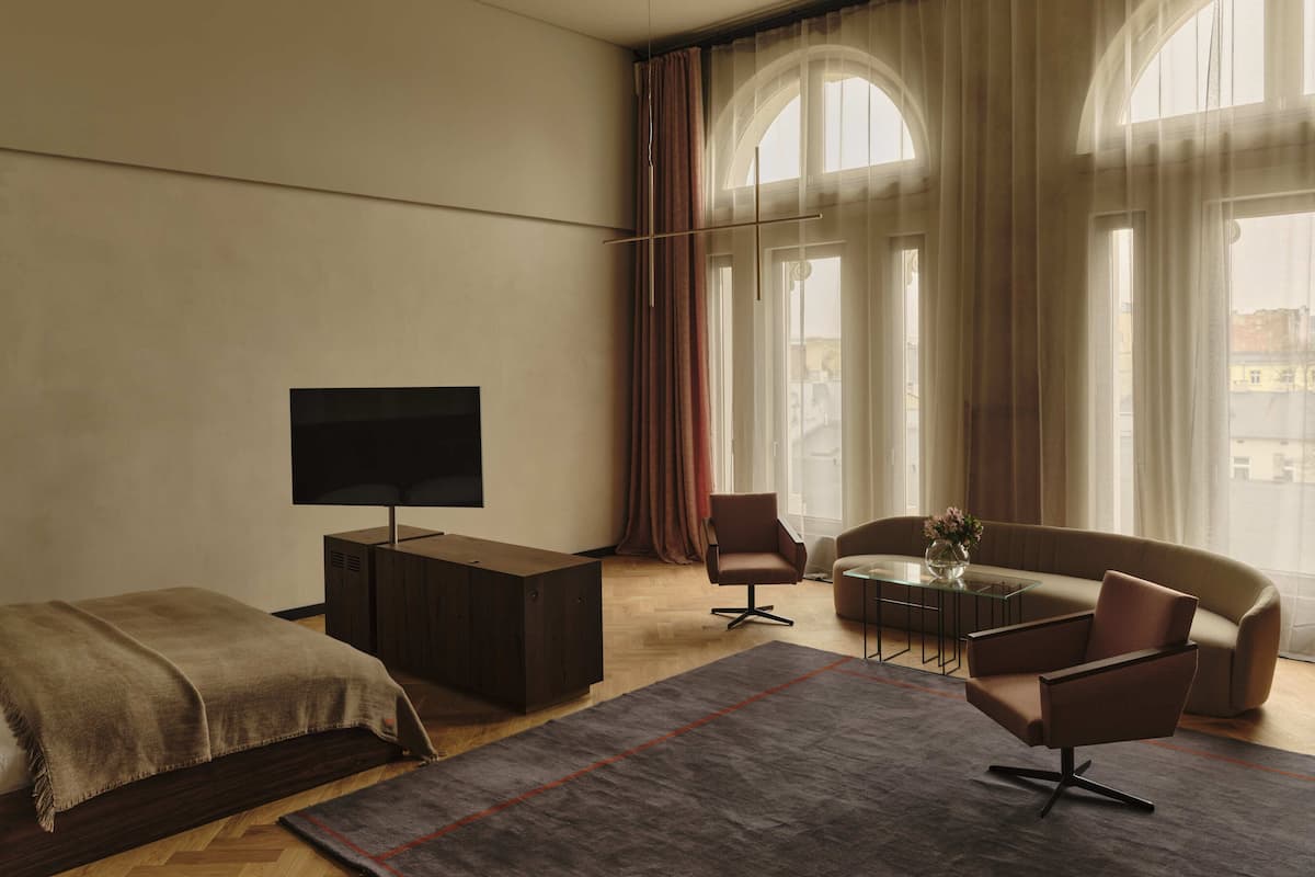 Habitación de hotel moderna con un ventanal grande, un televisor de pantalla plana, un sofá, una mesa de centro y una cama.