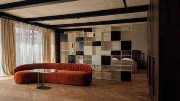 Una habitación moderna con suelo de madera, un sofá, una mesa de vidrio y una estantería empotrada.