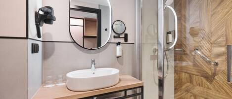 Un baño moderno con un espejo grande, un lavamanos y una ducha.