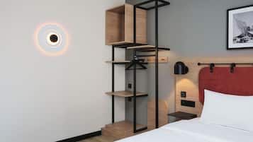 A modern hotel room with a bed, a red headboard, a wall-mounted shelf unit, and a circular light fixture.