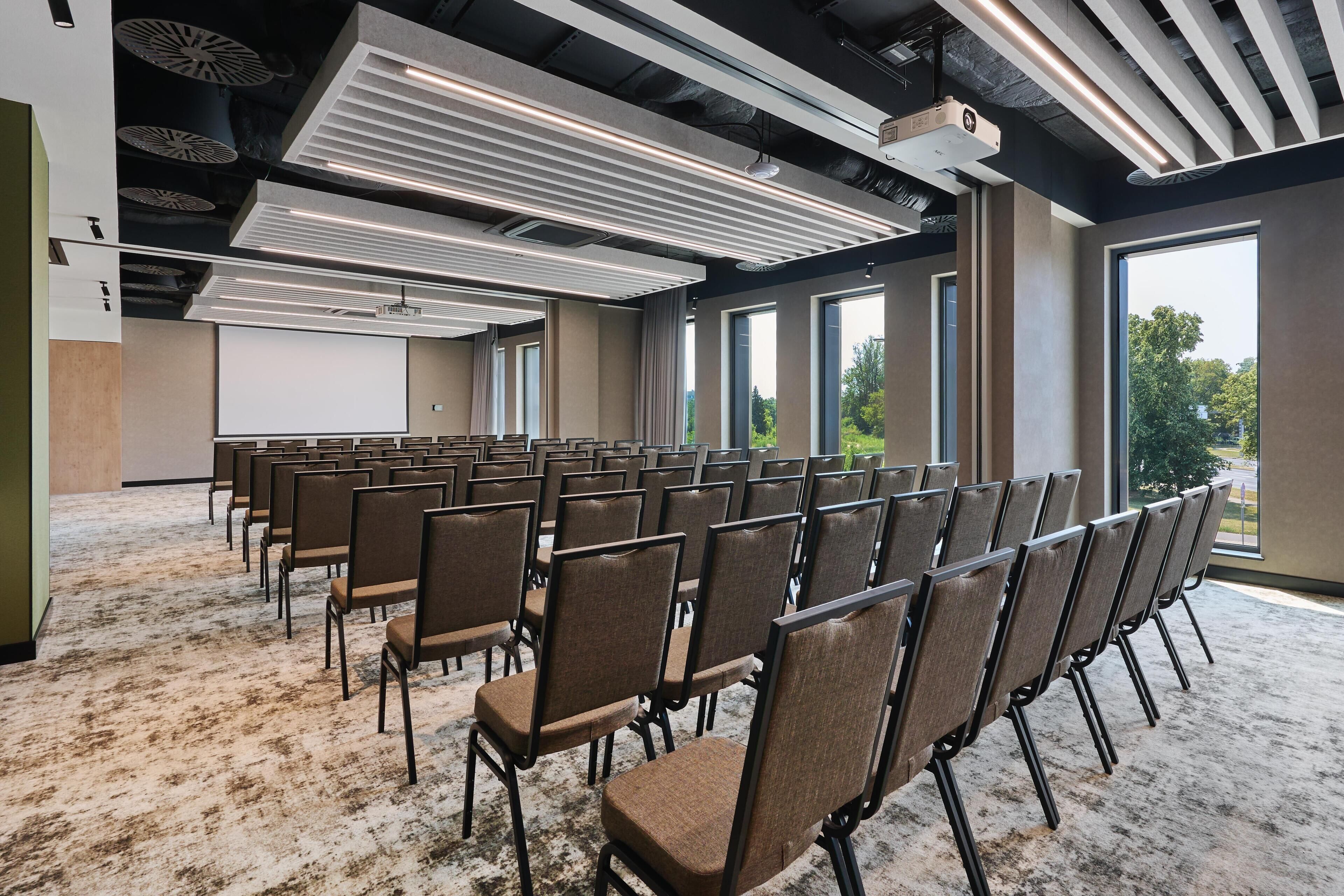 A conference room with rows of chairs, a projector, and large windows.